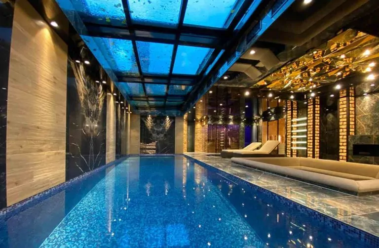 Retractable glass roof over an indoor luxury pool with marble finishes